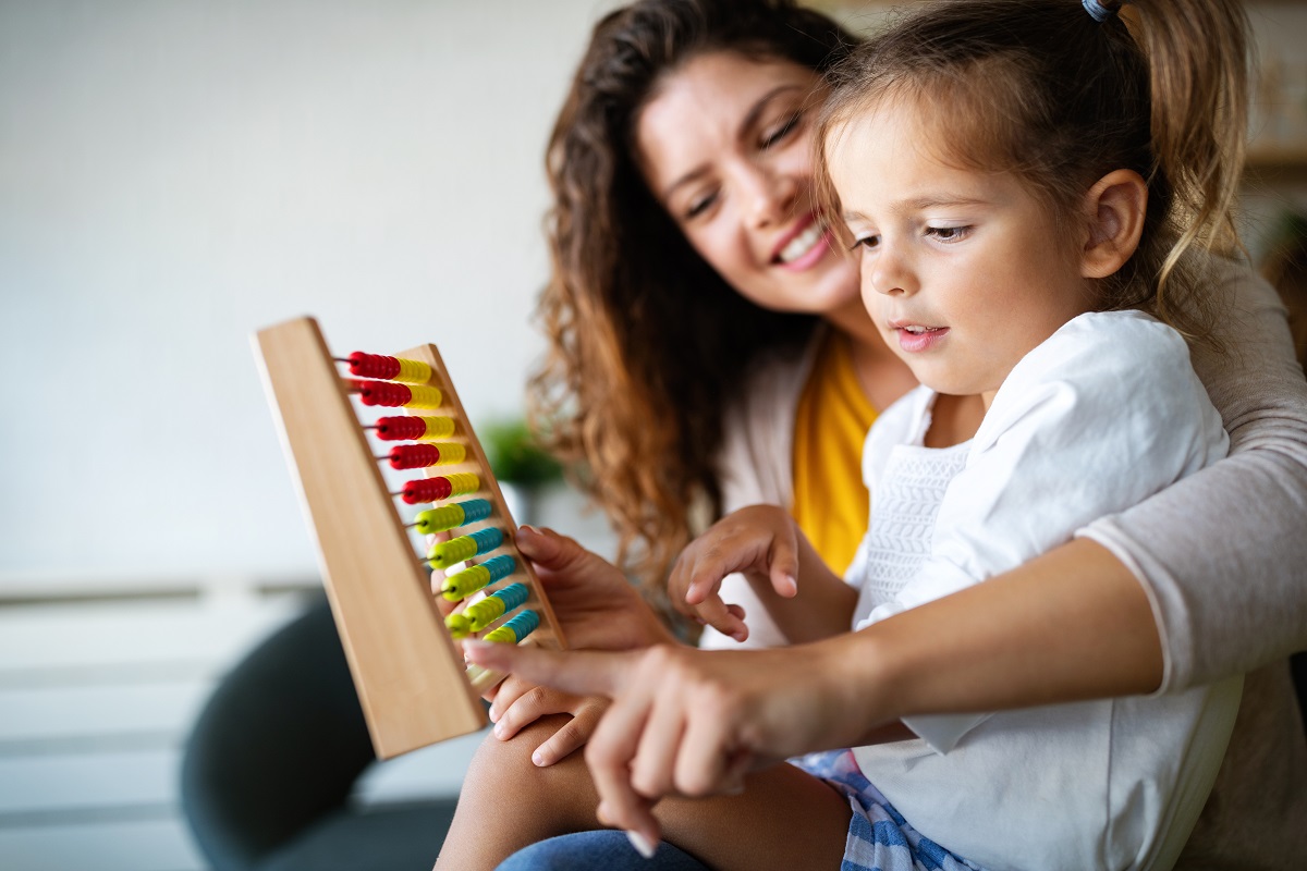 Mother and little cute girl playing with abacus