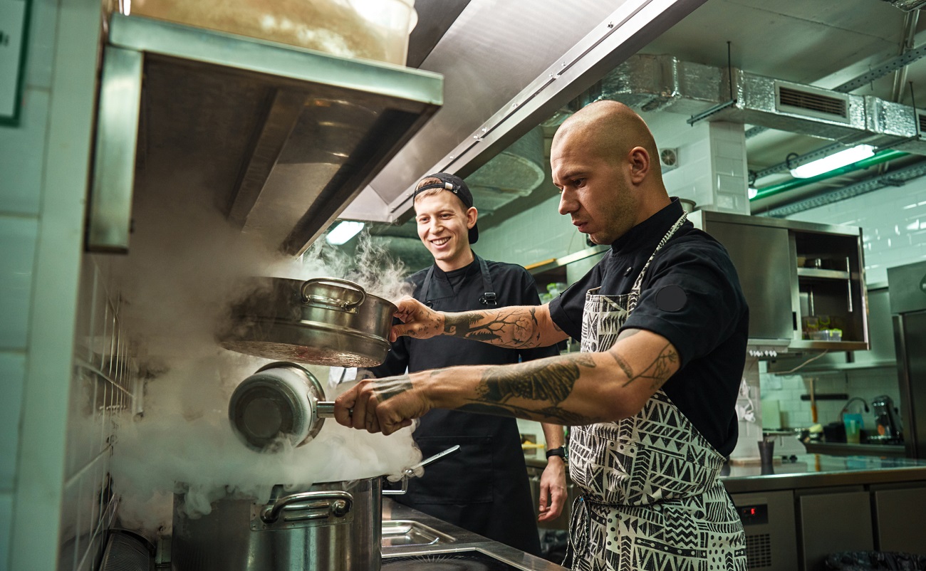 chef teaching his assistant how to cook in a restaurant kitchen