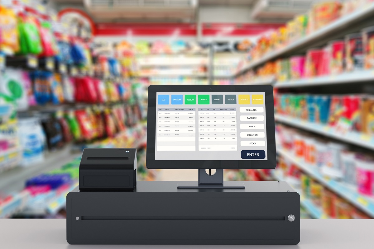 Closeup of cash register with grocery store aisles in background