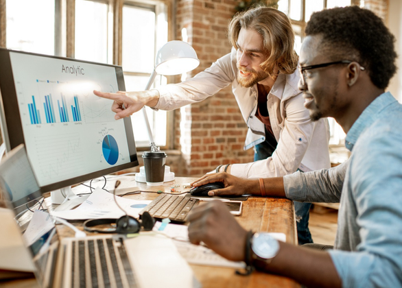 Two males working at a computer with graphs