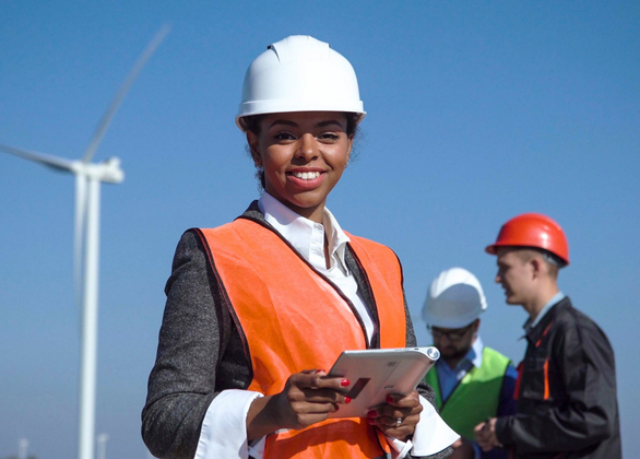 Woman with protective helmet against wind turbine 