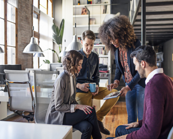 Four office workers looking at a tablet