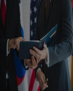 Business leaders sign document with American flag in background