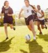 girls playing soccer in field