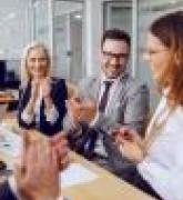 Colleagues clapping to their female colleague in boardroom