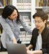 Female counselor checks student work on laptop