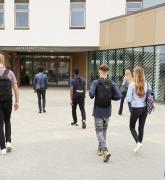 Rear view of high school students walking into a building