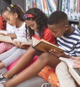 School kids sitting on cushions and studying over books in a library