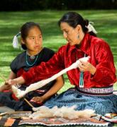Native American woman teaches weaving to a young girl