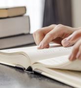 Stack of books, hands touching open book