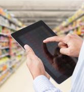 Businessman checking inventory in minimart on touchscreen tablet