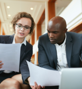 Two business partners sitting in café discussing contract.