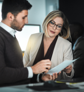 A man and a woman in an office discussing a document.
