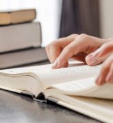 Stack of books, hands touching open book