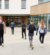 Rear view of high school students walking into a building