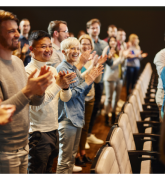 People standing and applauding in an auditorium