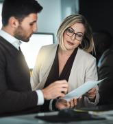 A man and a woman in an office discussing a document.